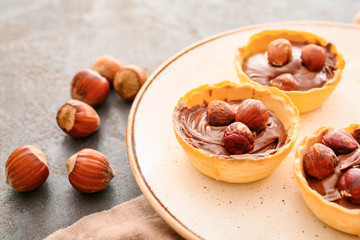 Tartlets with tasty chocolate paste and hazelnuts on plate