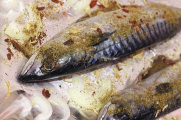 Mackerel fish is ready for baking. Fish is showered with tasty and aromatic seasonings and folded on foil.