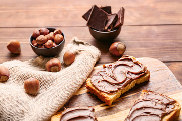 Board with fresh bread and chocolate paste on table