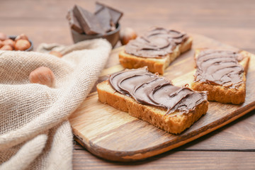 Board with fresh bread and chocolate paste on table