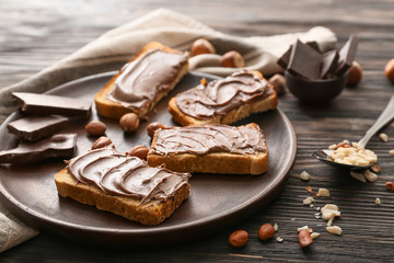 Plate with fresh bread and chocolate paste on table