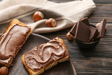 Plate with fresh bread and chocolate paste on table