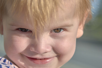Close up of the face of a smiling little girl with blond hair