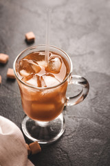 Cup of tasty iced coffee on dark background