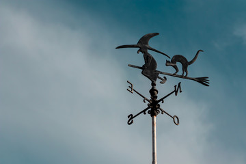 Weather vane of a witch flying on her broom with scared cat behind.