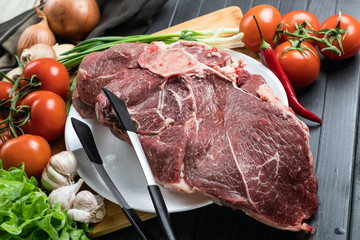 Fresh meat with cooking ingredients on a dark background. Juicy beef on a plate. Meat and vegetables. Balanced diet.