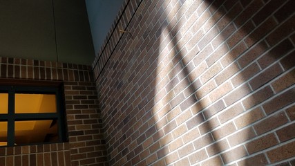 Window frame casting soft shadow on brick wall, concept of religious Christianity