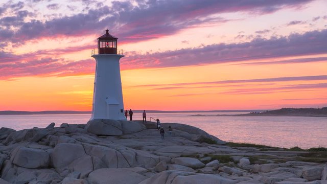 A day to night time-lapse of the Peggy's Cove Lighthouse on the Atlantic Coast, Nova Scotia, Canada. Dramatic clouds with the reflections of the historical lighthouse during sunset.