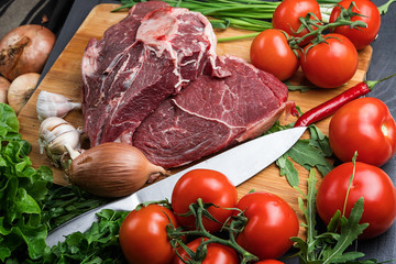 a piece of fresh choice beef lies on a wooden chopping Board. Fresh meat and vegetables Juicy steak with greens. Proper, balanced nutrition.