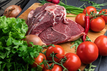 a piece of fresh choice beef lies on a wooden chopping Board. Fresh meat and vegetables Juicy steak with greens. Proper, balanced nutrition.