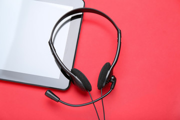 Tablet computer with headset on color background