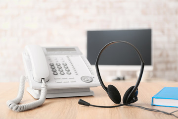 Headset and telephone on table of technical support agent in office