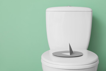Toilet bowl with thumbtack on color background. Hemorrhoids concept