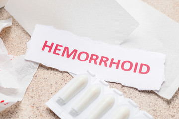 Paper with word HEMORRHOID and suppositories on light background
