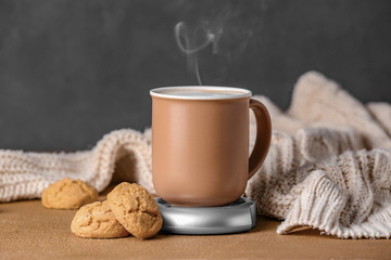 Cup of coffee with heater and cookies on table