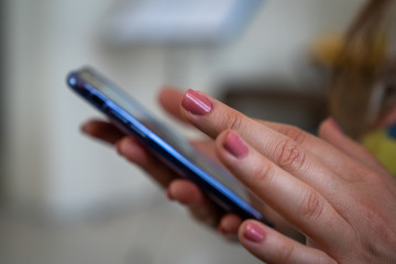 Selective focus of woman's hand writing message in a smart phone.
