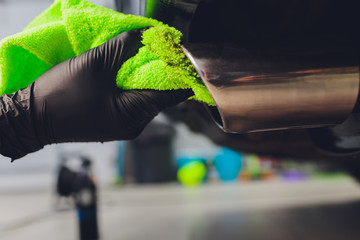 Car exhaust pipe with soap. Car wash background. close-up of a green rag