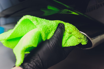 Car exhaust pipe with soap. Car wash background. close-up of a green rag