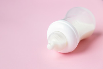 Baby milk bottle on a pink background with neagtive space. 