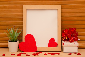Wooden frame with red hearts on a wooden table.