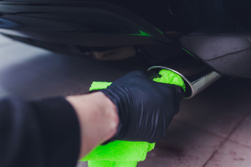 Car exhaust pipe with soap. Car wash background. close-up of a green rag