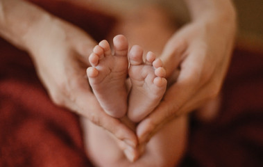 Mom's hands hold the legs of the baby