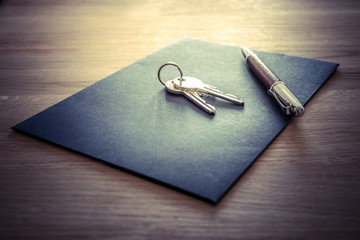 Keys, pen and envelope on the wooden table. Selling or rental of flat, house or another real estate or object. Symbol of agreement - obrazy, fototapety, plakaty
