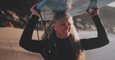 Close up senior woman running with surfboard at the beach - Powered by Adobe