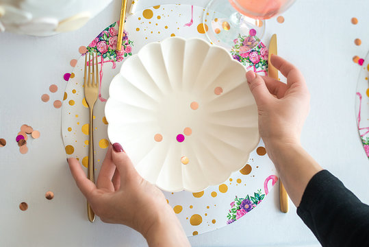 Decorator serving party table in white colors with beautiful white dishes, glasses for wine, golden cutlery. Happy birthday or baby shower for girl. Close up