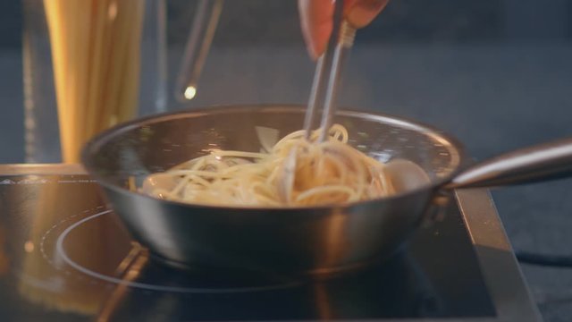 Traditional italian seafood pasta with clams Spaghetti alle Vongole
Chef toassing mussel pan
Hissing mussels in frying pan
add seasoning and sauce
close-up 4.6K