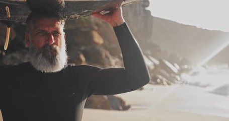 Close up senior handsome man carrying surfboard at the beach - Powered by Adobe