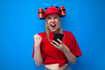 crazy funny girl a fan in a red uniform and a beer hat holds a smartphone and rejoices in victory, a fan is rooting for his team online