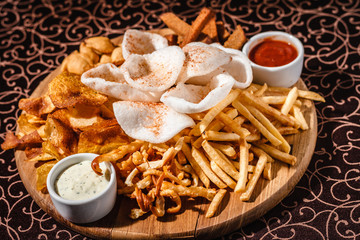 French fries and fried onions with sauce and on a wooden plate.