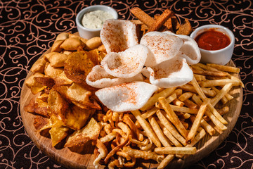 French fries and fried onions with sauce and on a wooden plate.