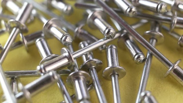 Aluminum rivet riveting machine for the construction of extremely close-up. All-in-one fasteners are on a yellow background. The camera moves forward