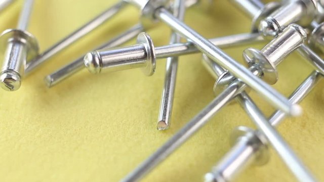 All-in-one fasteners are on a yellow background. Aluminum rivet riveting machine for the construction of extremely close-up.  The camera moves away