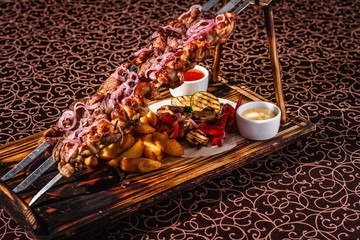 Skewers on skewers with potatoes and sauces.