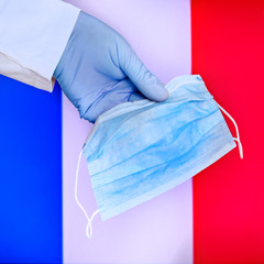 Protective mask in France, concept coronavirus pandemic. Hand in a medical glove holds a mask to protect from the pandemic flu virus among French.