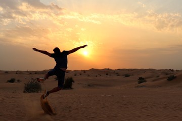 Fototapeta premium happy young man jumping on the beach at sunset