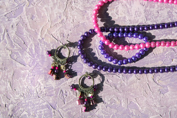 purple earrings and beads on a texture background out of focus