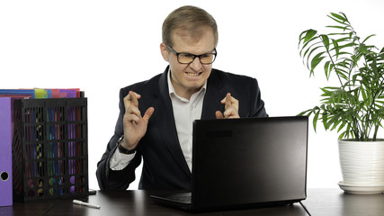 Businessman working in office. Prays, crosses his fingers, waits for good result