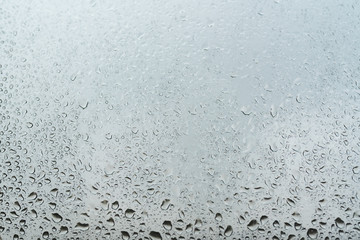 Water droplets on the window glass grey background. Selective focus.