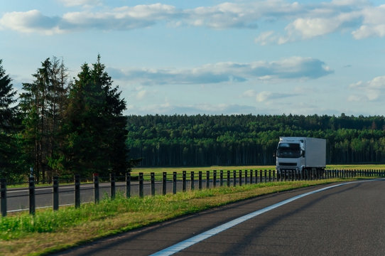 truck moving on a highway in Belarus against a background of green forests and fields