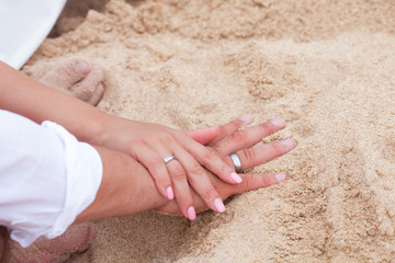 Bride and groom exchanging wedding rings close up during symbolic nautical decor destination wedding marriage on sandy beach in front of the ocean in Punta Cana, Dominican republic  