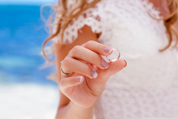 Bride and groom exchanging wedding rings close up during symbolic nautical decor destination...
