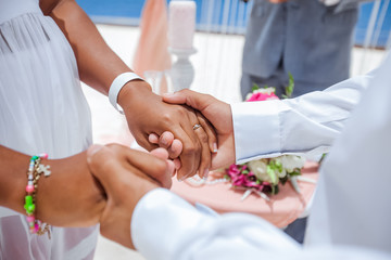 Obraz na płótnie Canvas Bride and groom exchanging wedding rings close up during symbolic nautical decor destination wedding marriage on sandy beach in front of the ocean in Punta Cana, Dominican republic 