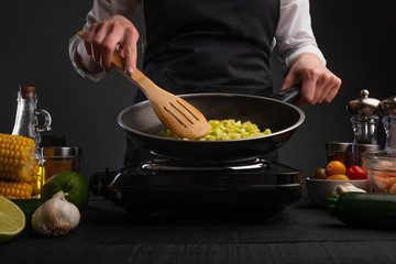 Chef fry vegetables in a pan. Against the background of ingredients, cooking in cafes, restaurants, healthy and wholesome food