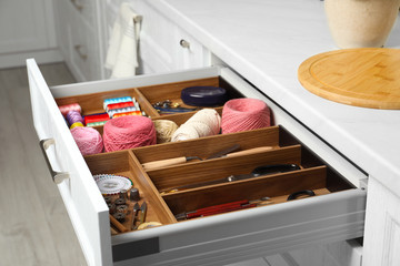 Fototapeta na wymiar Sewing accessories in open desk drawer indoors
