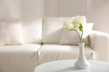Beautiful white freesia flowers in light room, space for text