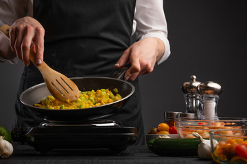Chef cooks frying vegetables on the background of ingredients. Cooking, tasty and wholesome food. Book of home recipes.